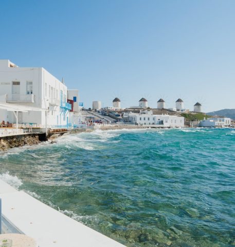 Beautiful view of the windmills built on a hill and the crystal clear sea on Mykonos island.