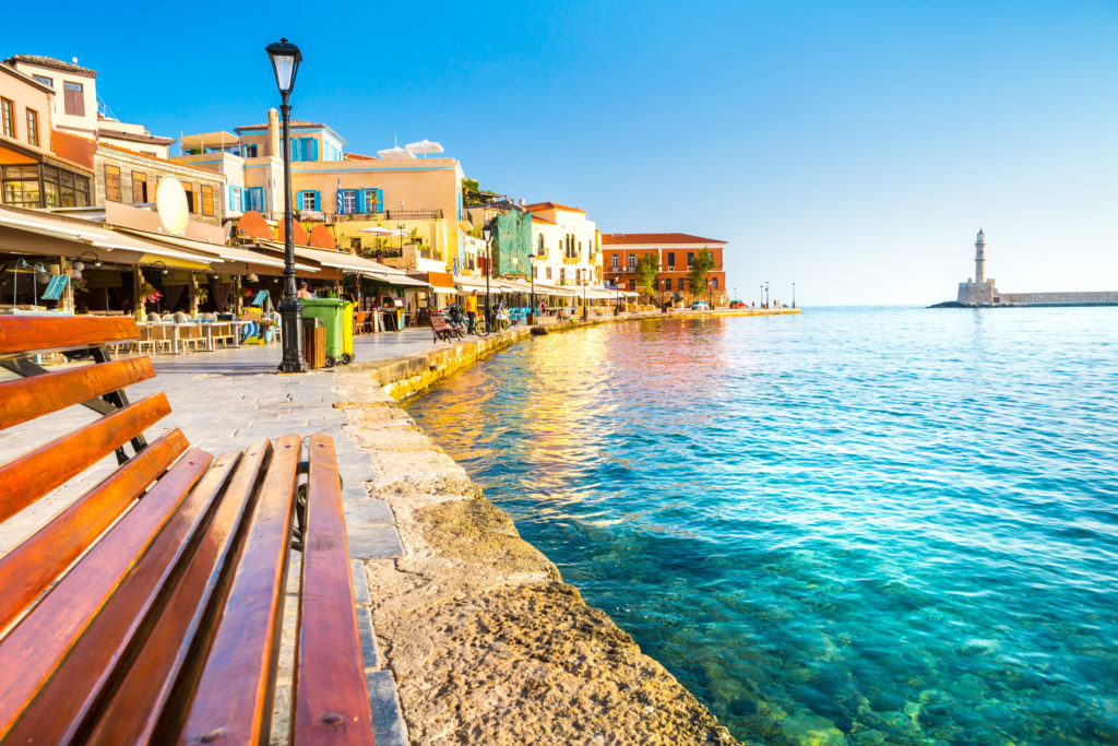 Bench by the sea and the beautiful city of Chania at the back.