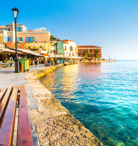 Bench by the sea and the beautiful city of Chania at the back.