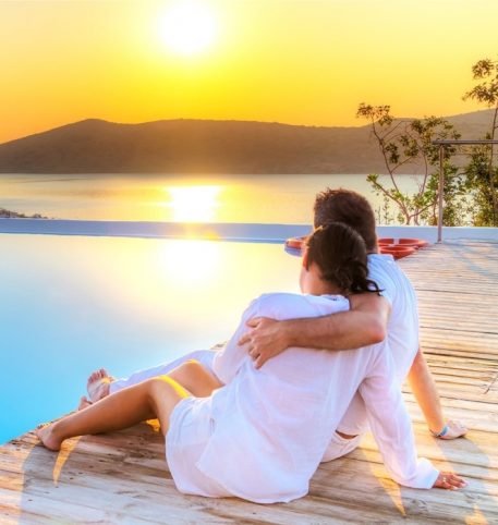 Couple sitting by the pool admiring the sea. Romantic holiday in Athens Mykonos Santorini.