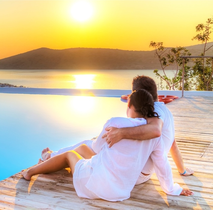 Couple sitting by the pool admiring the sea. Romantic holiday in Athens Mykonos Santorini.