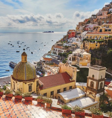 Traditional italian houses and a church with the characteristic dome overlooking the sea.