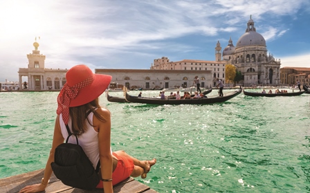 Lady sitting by the edge of a canal in Venice, overlooking the gondolas.