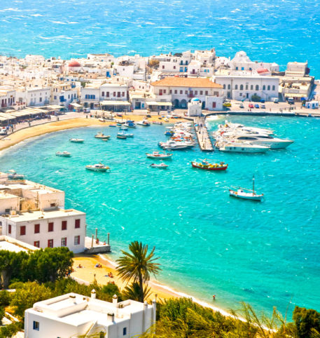 Boats in a bay and panoramic view of a village on one of the Greek islands. Crystal clear sea water.