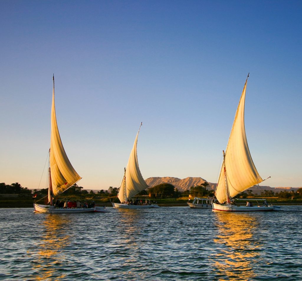 Sailing boats in the Nile River and sand dunes at the back. Egyptian Delight Egypt holidays.